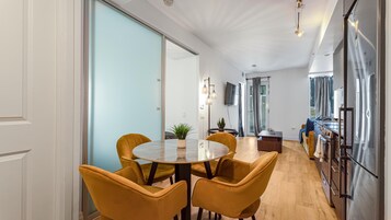 Een moderne keuken met een inbouwoven en een eethoek met een ronde tafel en gele stoelen.