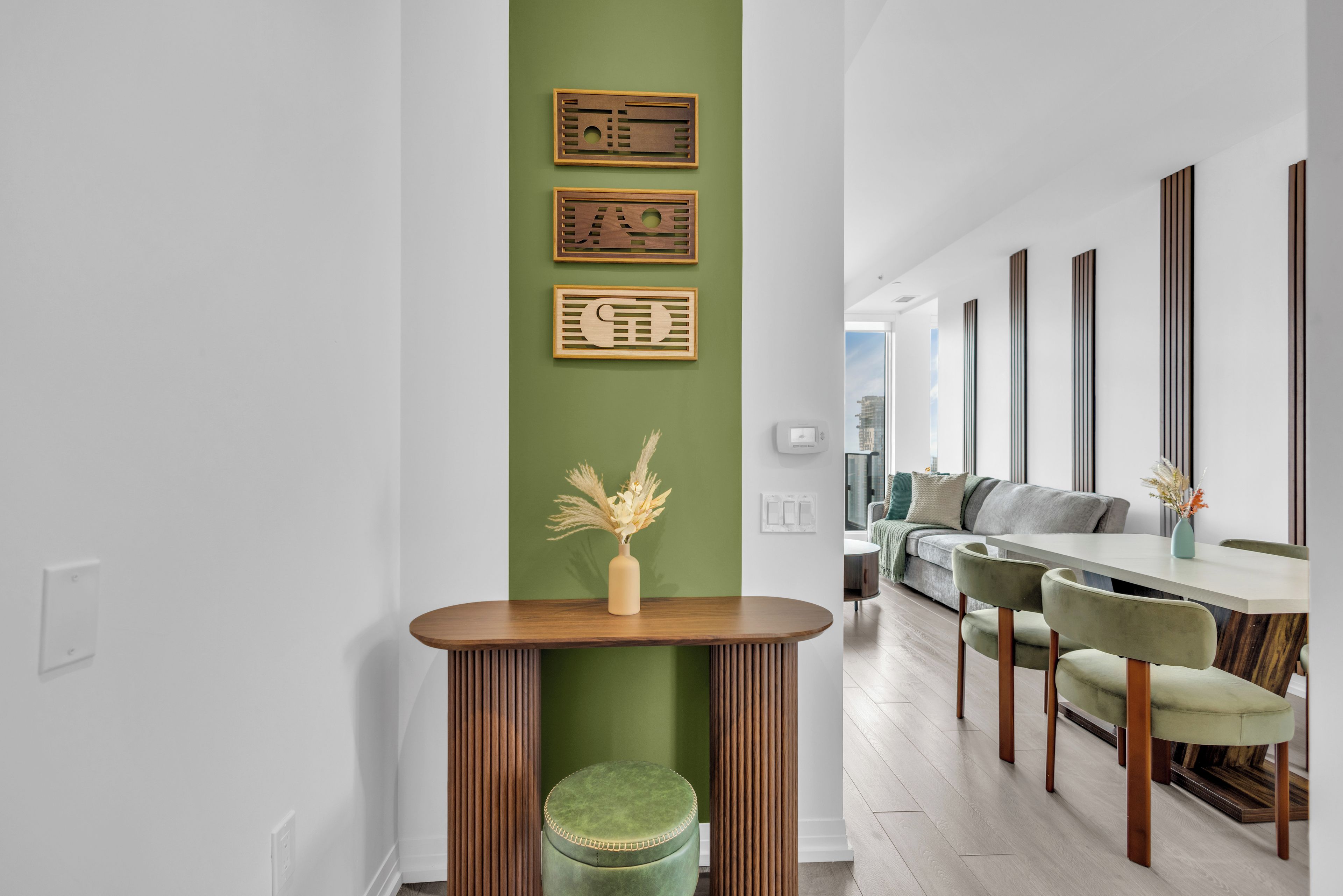 Un interno moderno con zona pranzo, parete verde decorativa e pannelli di legno ornamentali.