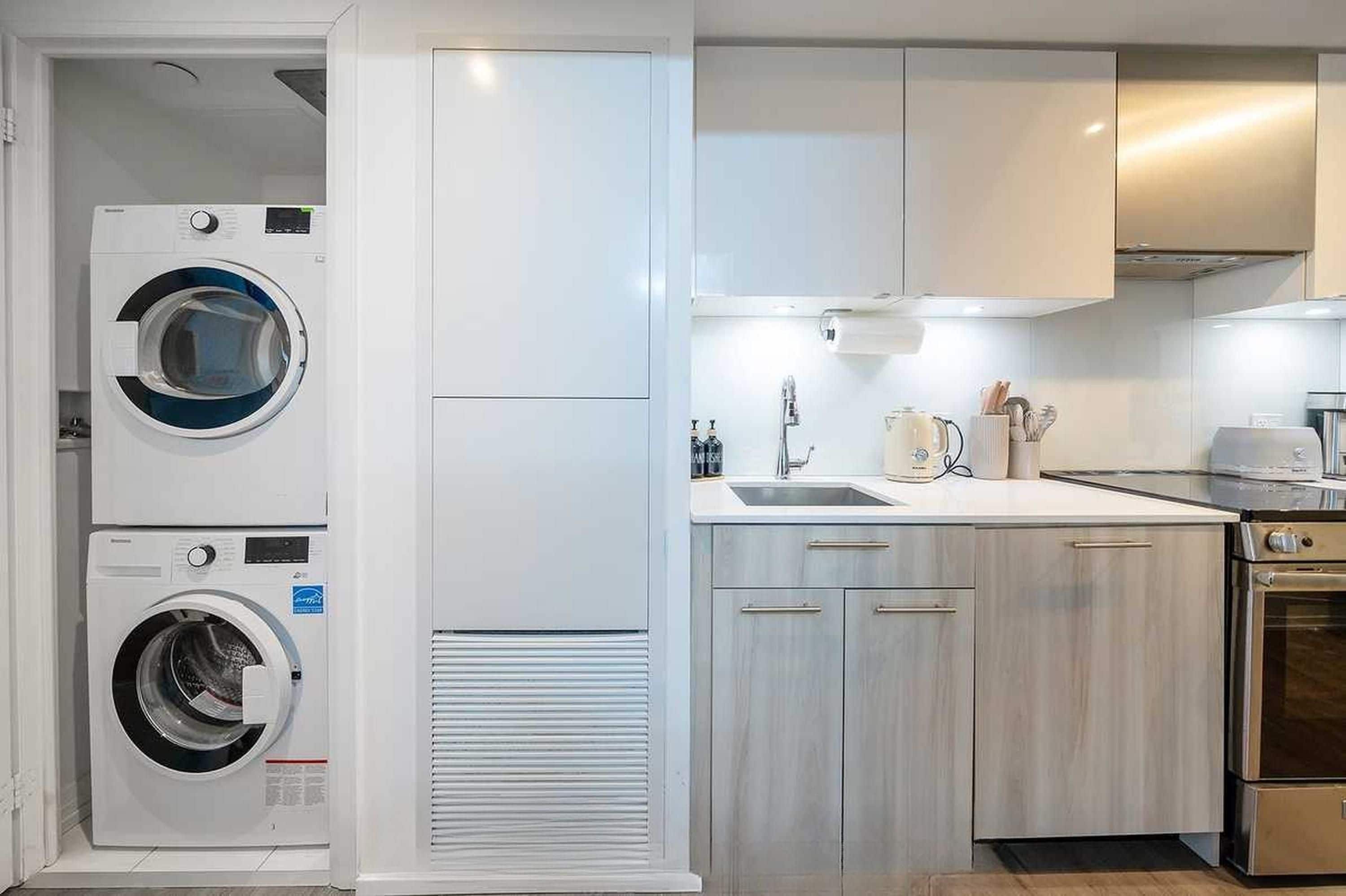 A compact kitchen with a washing machine, a sink, and a stove.
