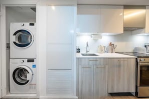 A compact kitchen with a washing machine, a sink, and a stove.