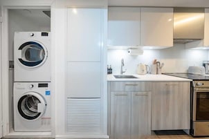 Een kleine keuken met een wasmachine, een spoelbak en een fornuis.
