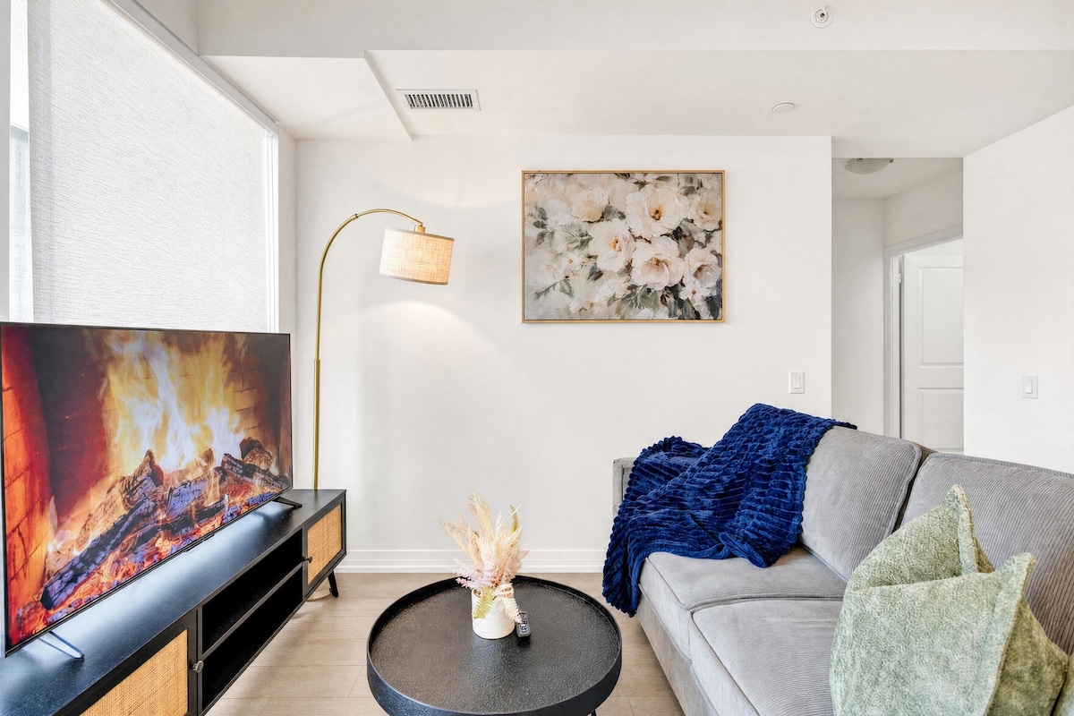 A living room with a flat-screen TV, a floor lamp, a sofa, a coffee table, and a painting on the wall.