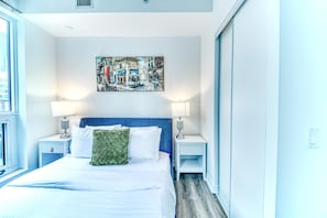 A hotel room with a bed, two bedside tables, a painting on the wall, and a window. - StayToronto - The Jarvis Condos (Toronto)