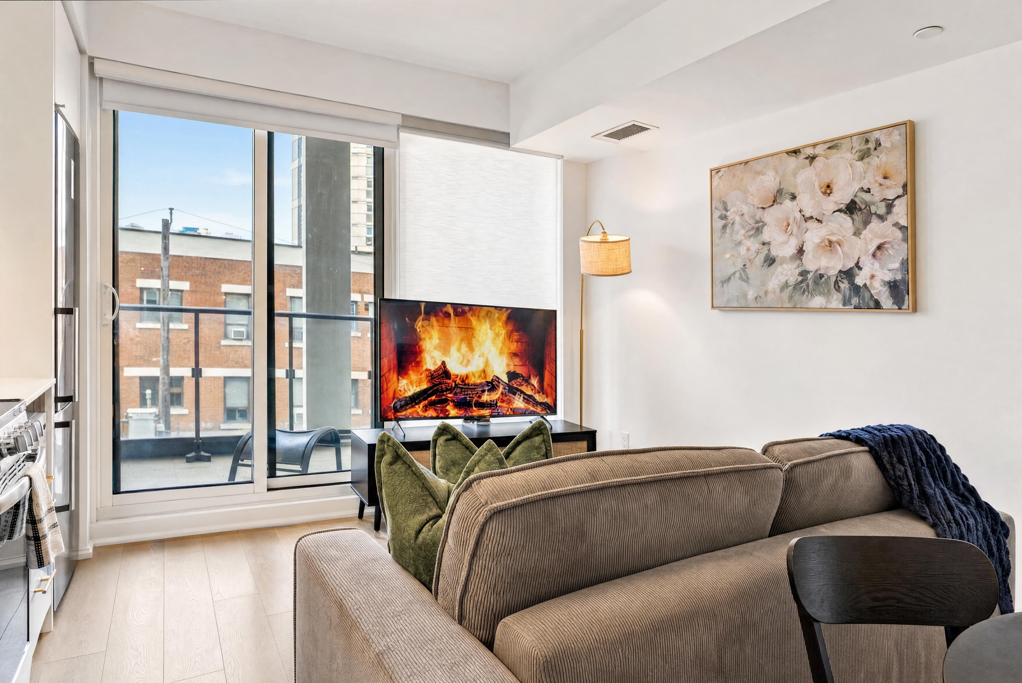 Uma sala de estar moderna com uma televisão grande, um sofá e um quadro na parede.