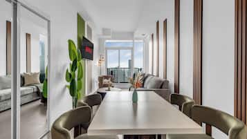 Een moderne woonkamer met een eethoek, een groot raam en uitzicht op de stadshemel.