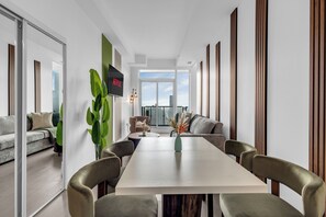 Una sala de estar moderna con comedor, un ventanal y vistas al horizonte de la ciudad.