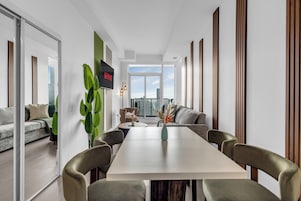 Een moderne woonkamer met een eethoek, een groot raam en uitzicht op de stadshemel.