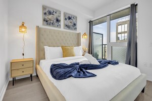 Een slaapkamer met een groot bed, twee nachtkastjes, een raam met uitzicht en twee wandlampen.