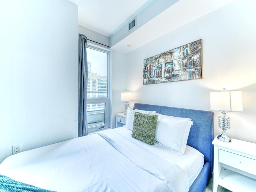 A hotel room with a large bed, a nightstand, a lamp, and a window with curtains.