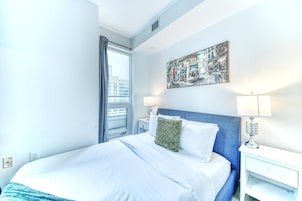 Een hotelkamer met een groot bed, een nachtkastje, een lamp en een raam met gordijnen.