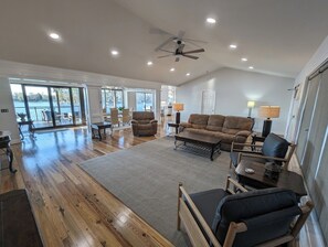 A spacious living area with a large window, a ceiling fan, and a fireplace. - Best View on Lake Murray in Chapin (Chapin)