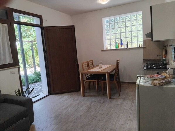 A compact kitchen with a dining table, a built-in stove, and a window with a view of greenery.