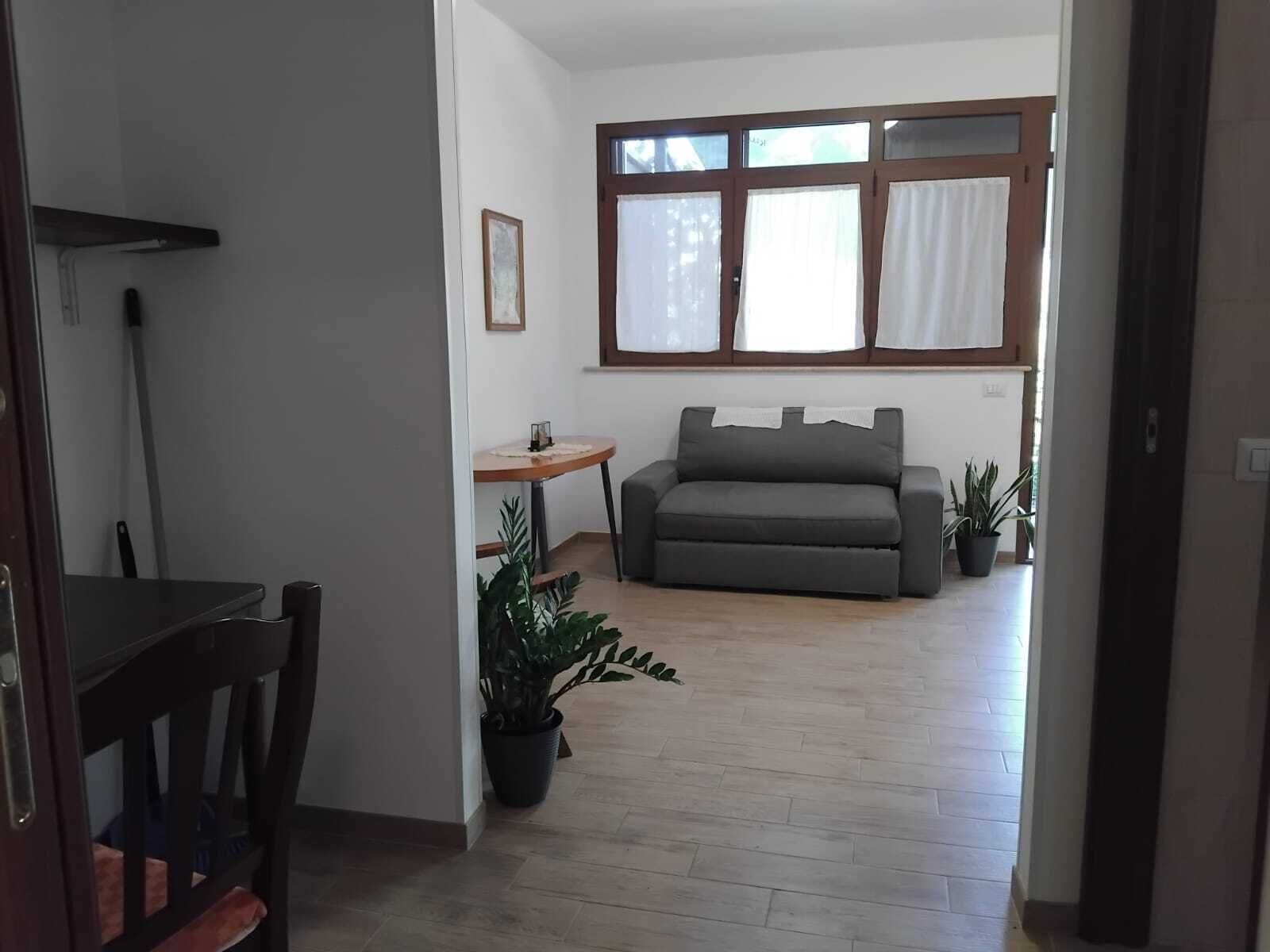 Ein Wohnzimmer mit einer Couch, einem kleinen Tisch und einer Zimmerpflanze.