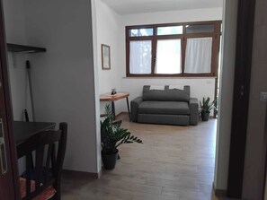 A living room with a sofa, a small table, and a potted plant.