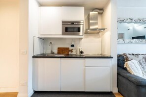 A compact kitchen with white cabinets, a stainless steel oven, and a microwave. - Appartamento di charme (Florence)
