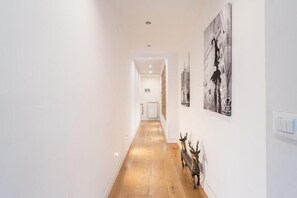 A hallway with white walls, wooden flooring, and black-and-white photographs on the walls. - Appartamento di charme (Florence)