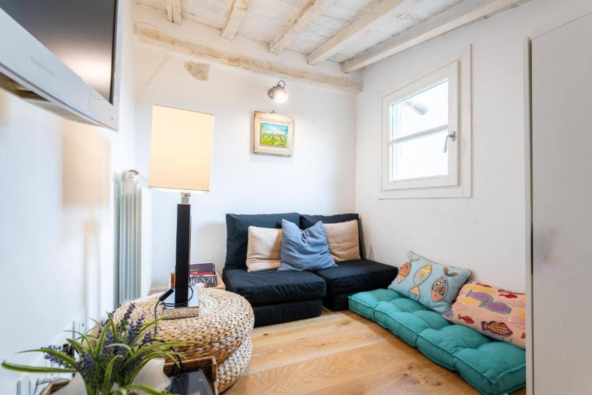 Ein gemütliches Wohnzimmer mit einem schwarzen Sofa, einem türkisblauen Sofa, einer Lampe und einem gerahmten Bild an der Wand.