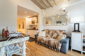 A cozy living room with a sofa, a dining table with chairs, a kitchen area, and a television on a stand. - Appartamento di charme (Florence)