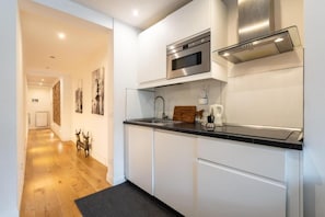 A modern kitchen with white cabinets, a stainless steel microwave, and a black countertop. - Appartamento di charme (Florence)