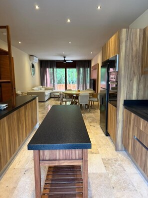 Eine moderne Küche mit einer zentralen Kochinsel, Holzschränken und einem Essbereich mit einer Couch und Stühlen.