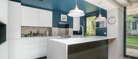 A modern kitchen with a central island, white cabinetry, and pendant lighting.