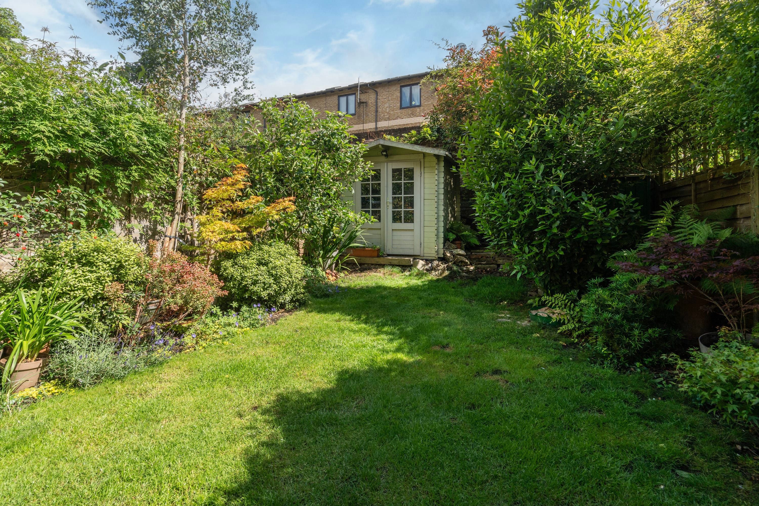A well-maintained garden with a variety of plants and a small shed.