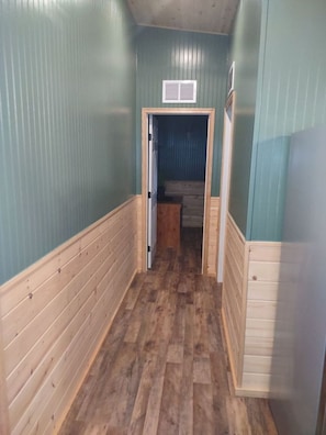 A narrow hallway with wooden paneling on the walls and a wooden floor.