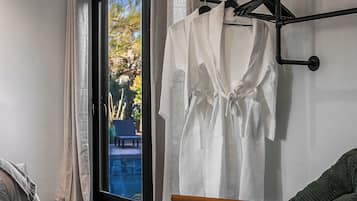 A room with a sliding glass door leading to a balcony, a wooden chair, and a rack with white towels.
