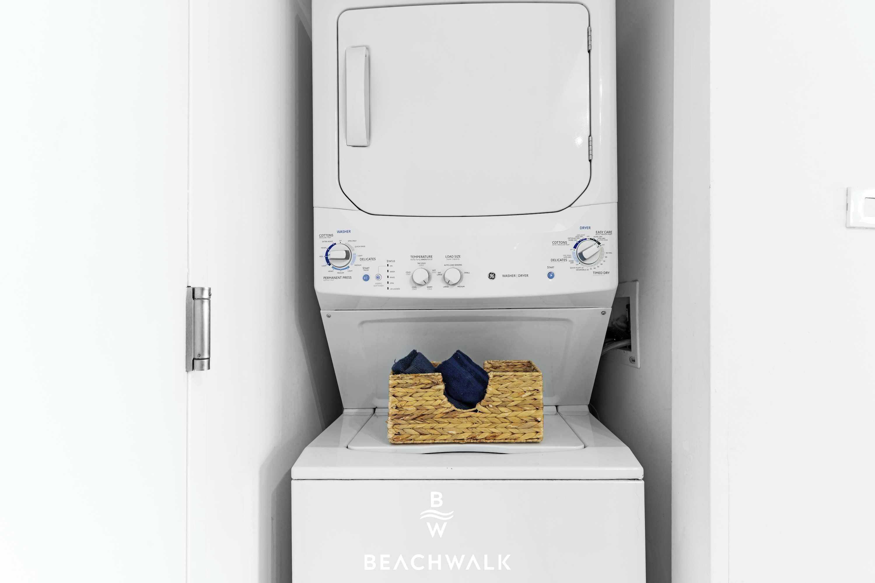A white washing machine with a basket of laundry inside, a control panel with various settings, and the brand name 'BEACHWALK' on the base.
