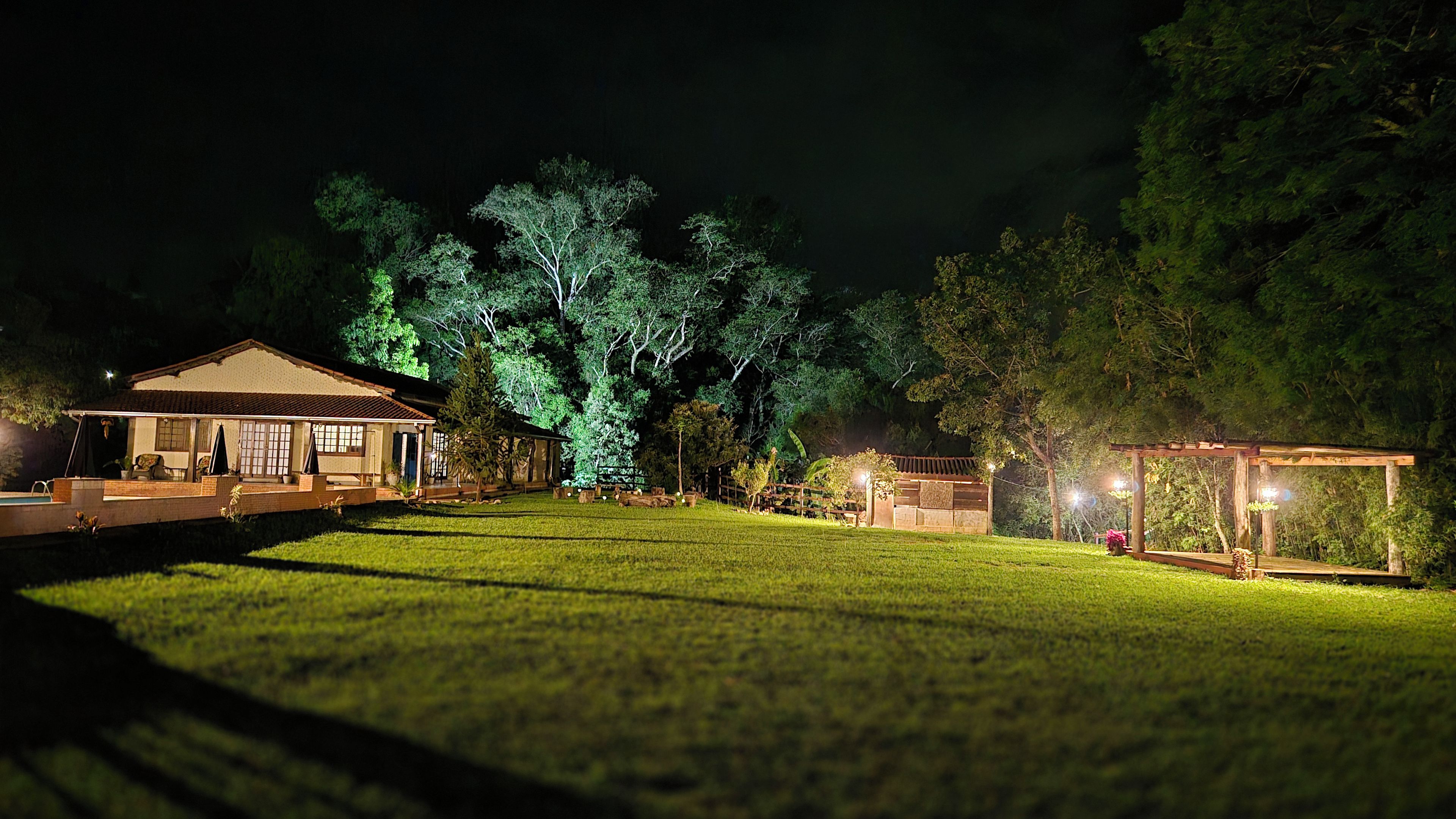 Uma casa com varanda coberta, gramado e árvores.