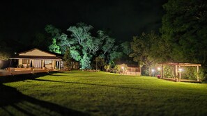Una casa amb terrassa coberta, gespa i arbres.