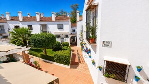 A courtyard with white buildings, a covered seating area, and potted plants. - Playa & Golf Townhouse - 2 min from MAJ Golf Academy (Torremolinos)