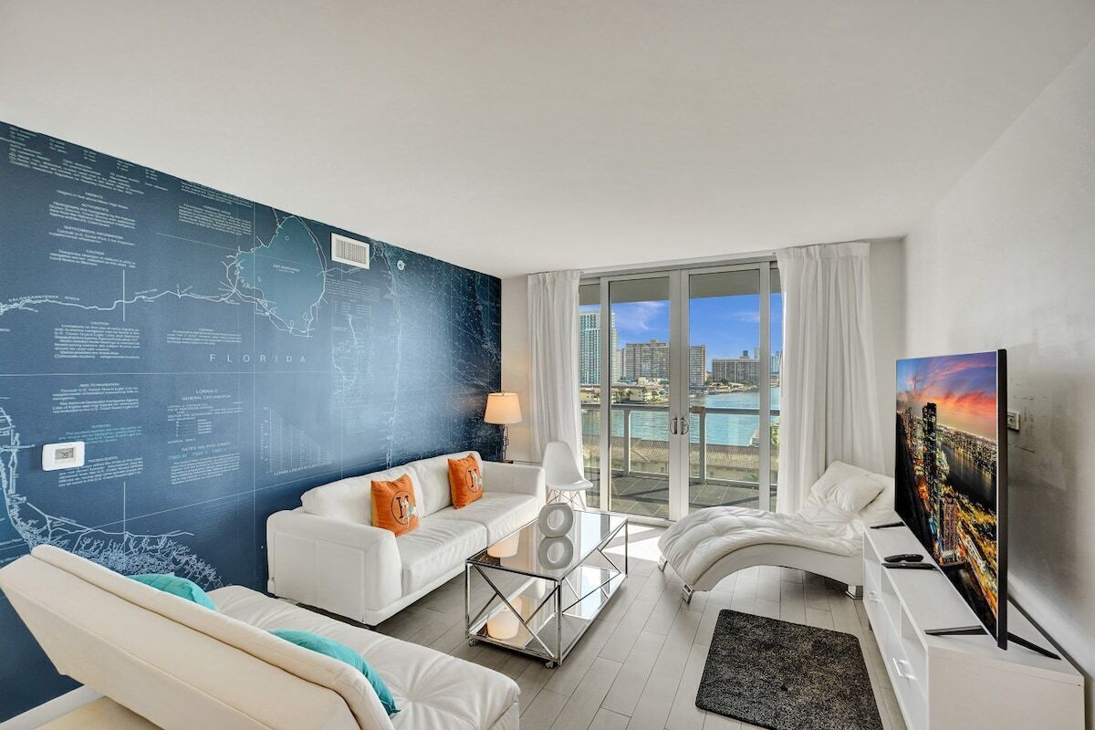 A modern living room with a large wall map, a white sofa set, a glass coffee table, and a flat-screen TV.