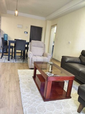 Ein Wohnzimmer mit einer Couch, einem Couchtisch, einem Esstisch mit Stühlen und einem Sessel.
