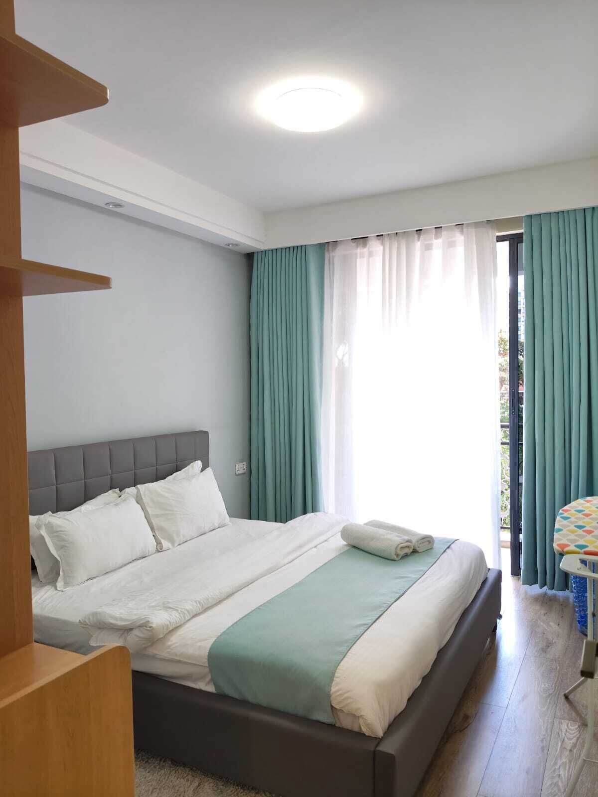 Ein Schlafzimmer mit einem Bett, einem Fenster mit Vorhängen und Blick nach draußen.