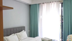 Ein Schlafzimmer mit einem Bett, einem Fenster mit Vorhängen und Blick nach draußen.