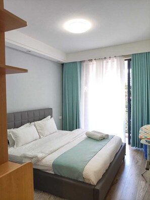 Ein Schlafzimmer mit einem Bett, einem Fenster mit Vorhängen und Blick nach draußen.