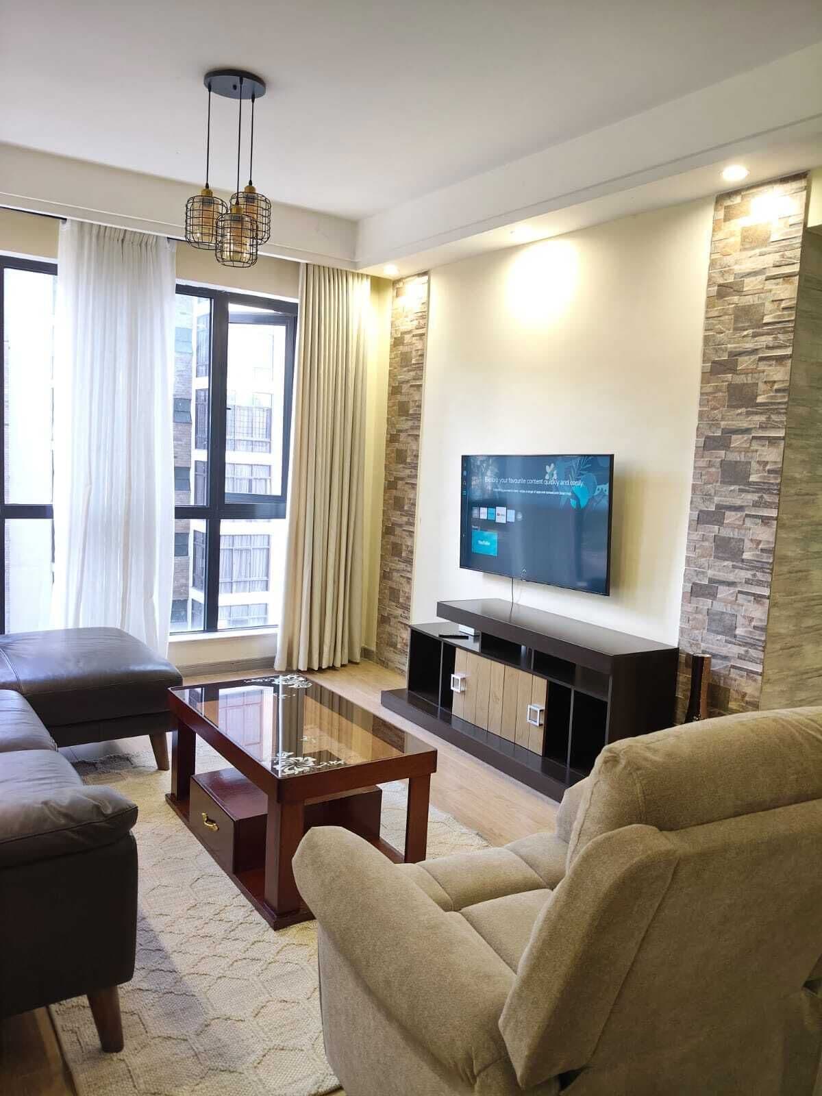 Ein modernes Wohnzimmer mit Flachbildfernseher, Ledersofa und Glastisch.