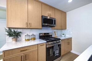 A kitchen with wooden cabinets, a stainless steel stove, and a microwave. - Modern 3BR Monterey Park Home Near LA & DTLA (Monterey Park)