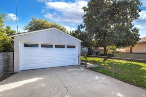 A single-story building with a garage door, surrounded by a chain-link fence, and a tree to the right. - Modern 3BR Monterey Park Home Near LA & DTLA (Monterey Park)