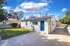 A single-story building with a blue door, a small front yard, and a paved driveway. - Modern 3BR Monterey Park Home Near LA & DTLA (Monterey Park)