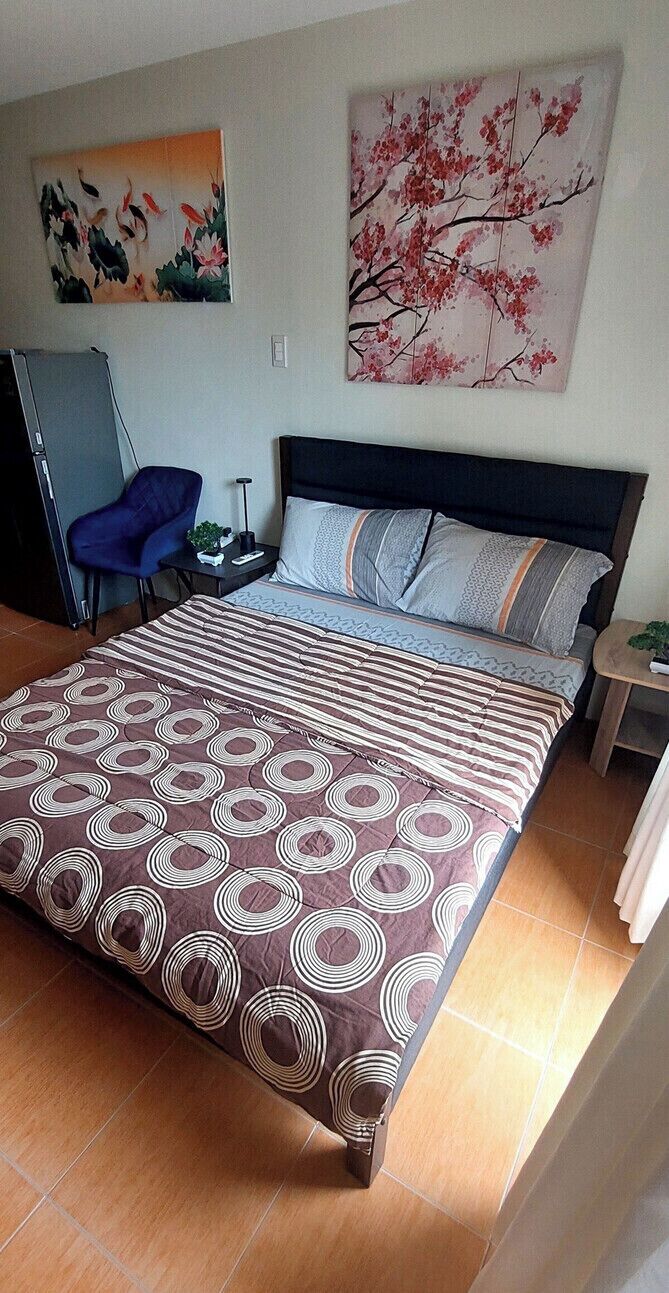 Une chambre à coucher comprenant un lit, une chaise, un bureau et deux tableaux accrochés au mur.