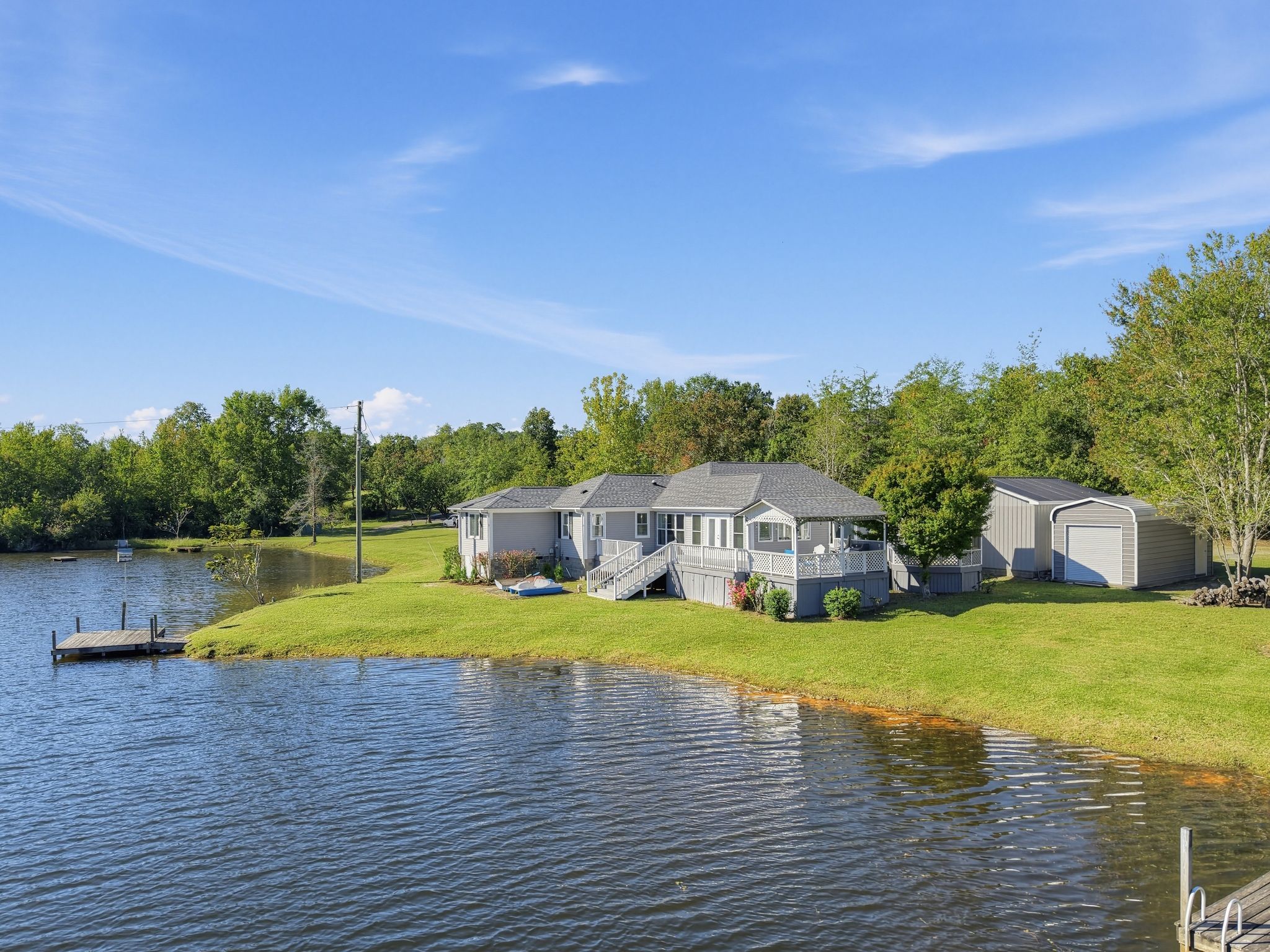 A lakeside property with a house, a dock, and a covered boat storage area.