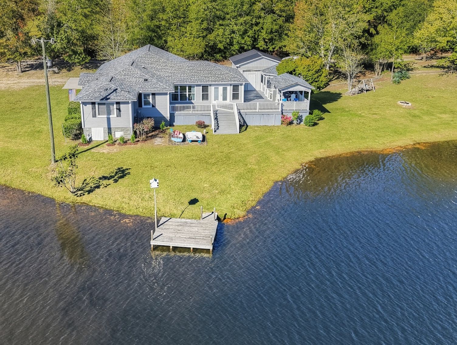 A two-story house with a dock extending into a body of water.