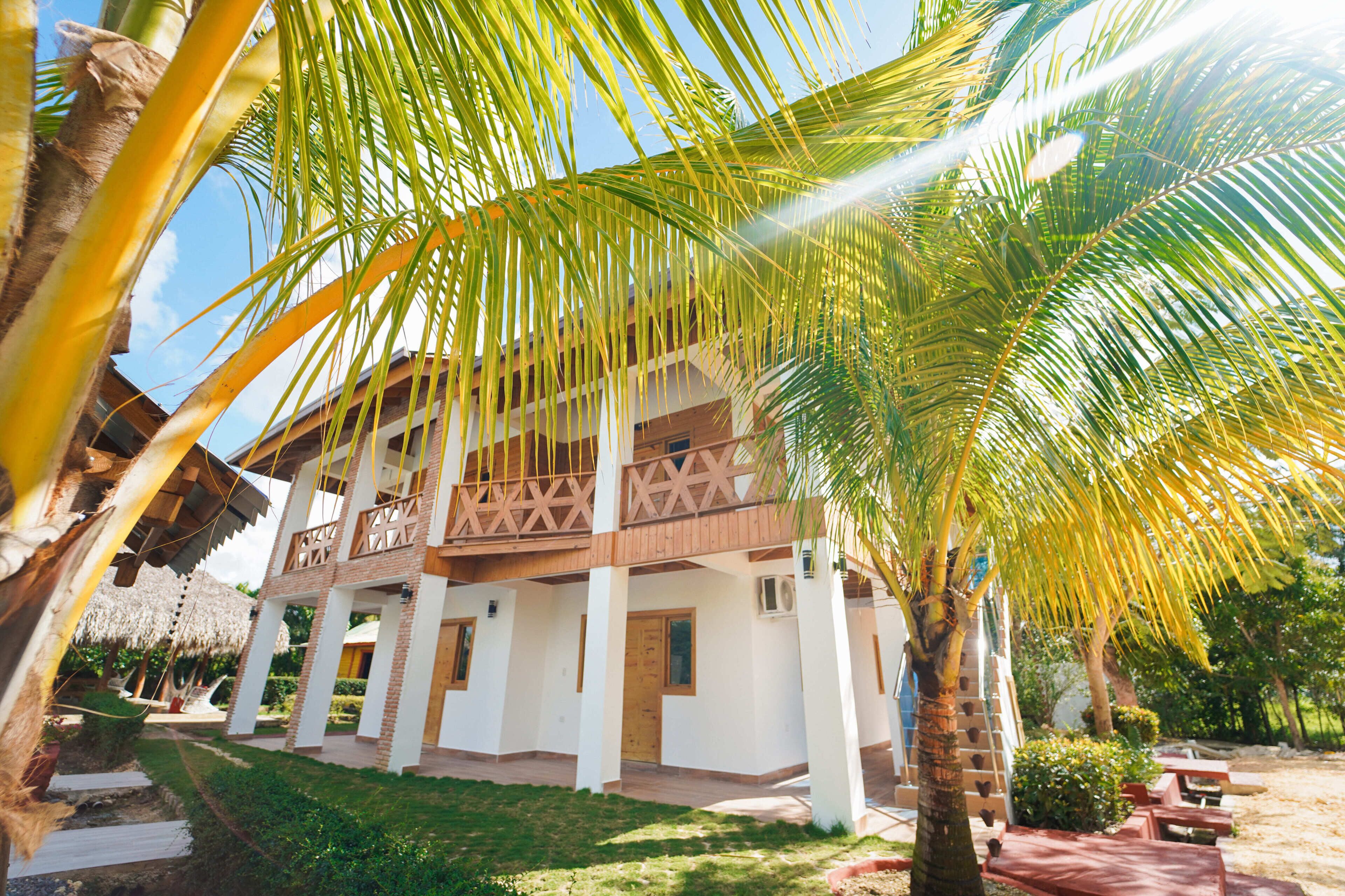 A two-story building with a balcony, surrounded by palm trees and a well-maintained lawn.