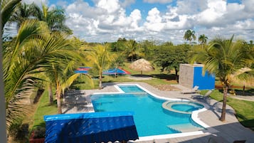 A swimming pool with a surrounding deck, palm trees, and a clear sky.