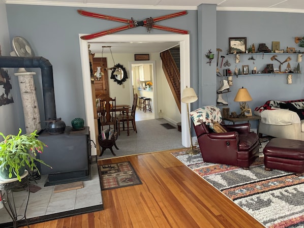 A cozy living room with a fireplace, a dining area, and a hallway leading to a kitchen.