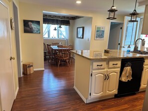 A kitchen with wooden cabinets, a granite countertop, and a black dishwasher.