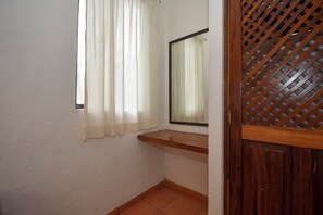 Une pièce avec une fenêtre, un miroir et une porte en bois ornée d’un motif en treillis.