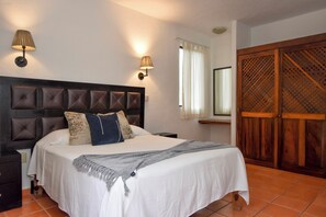 A bedroom with a bed, bedside lamps, a window with curtains, and a wooden wardrobe. - 2-bedroom apartment in peaceful Puerto Vallarta with AC (Puerto Vallarta)